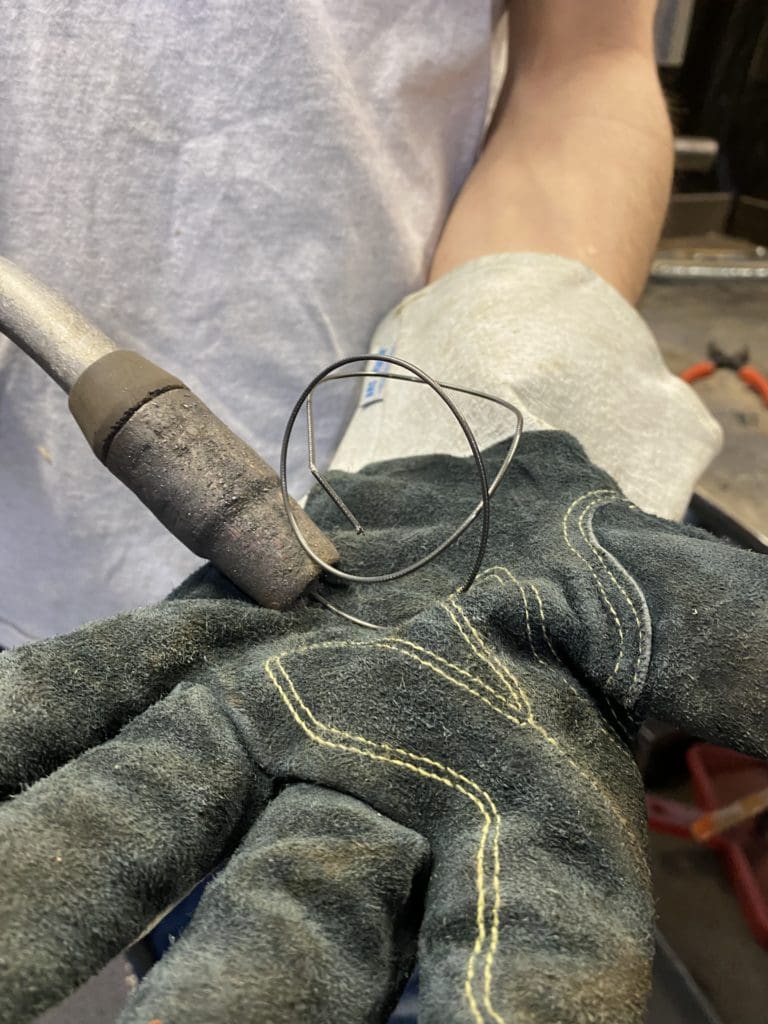 Primer plano del guante del operador de soldadura con pistola MIG que prueba la tensión del cable