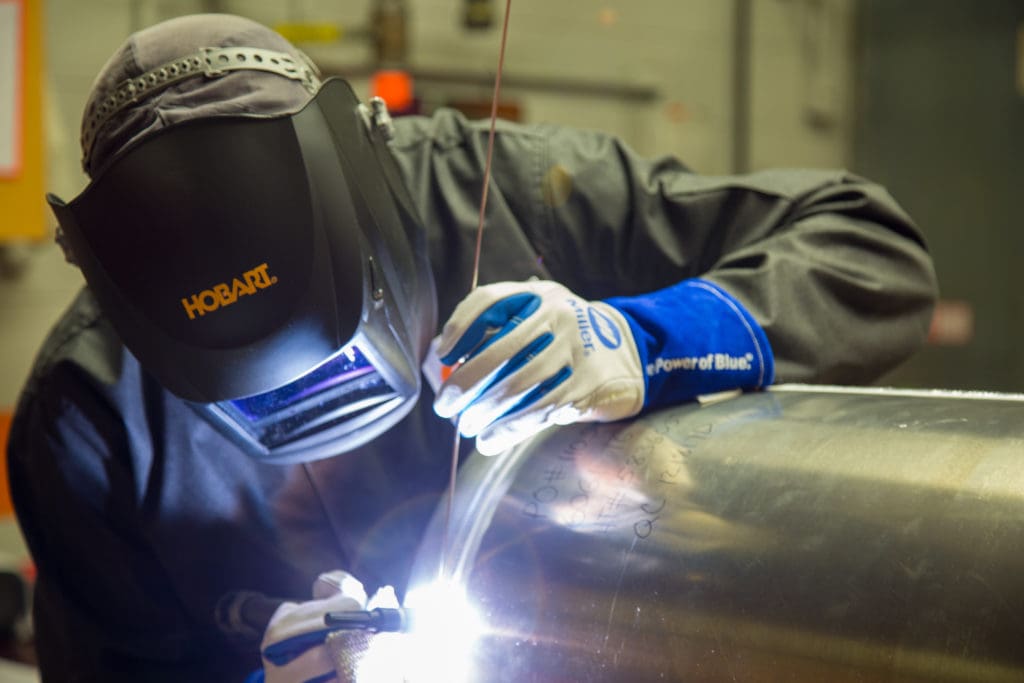 Closeup of welder TIG welding on large aluminum cylinder