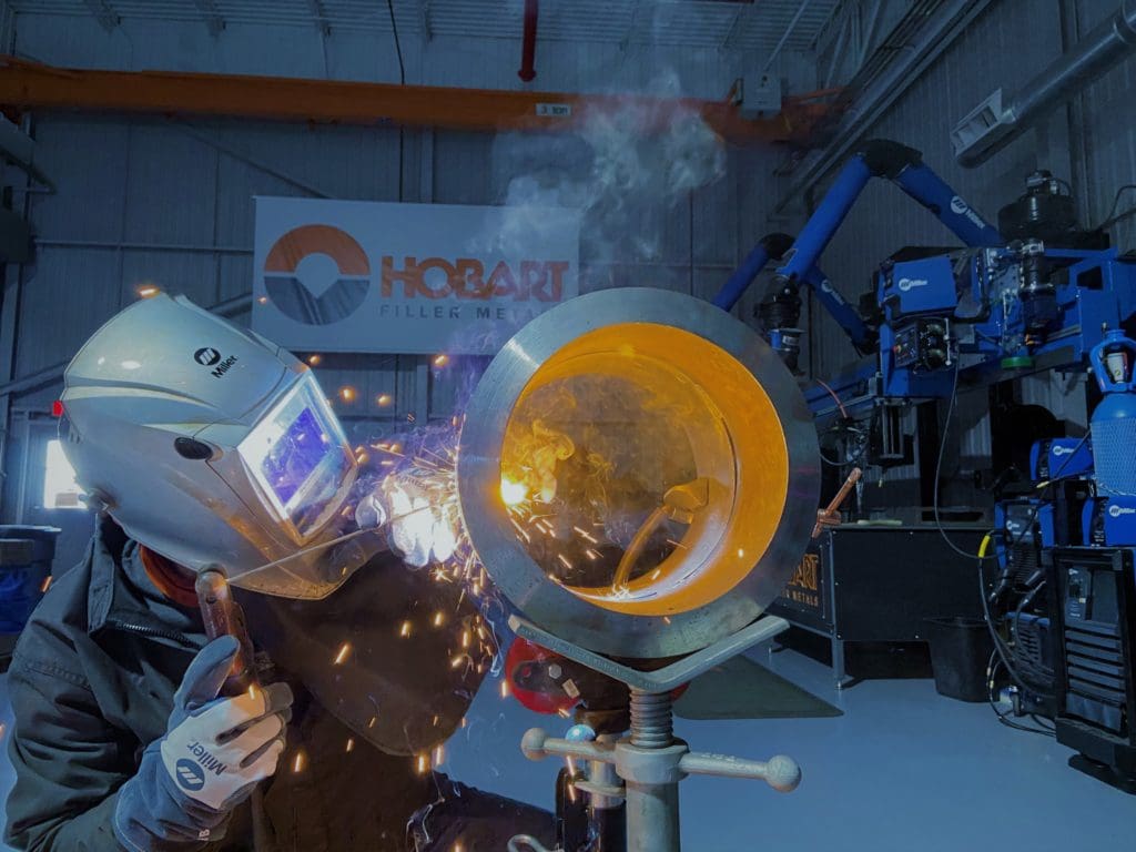 Side view of welding operator stick welding on a piece of pipe