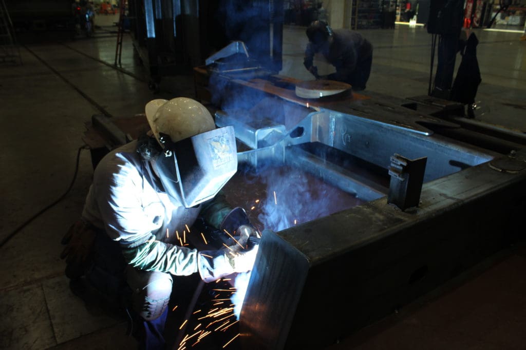 Welding operator kneeling to weld on large railcar component