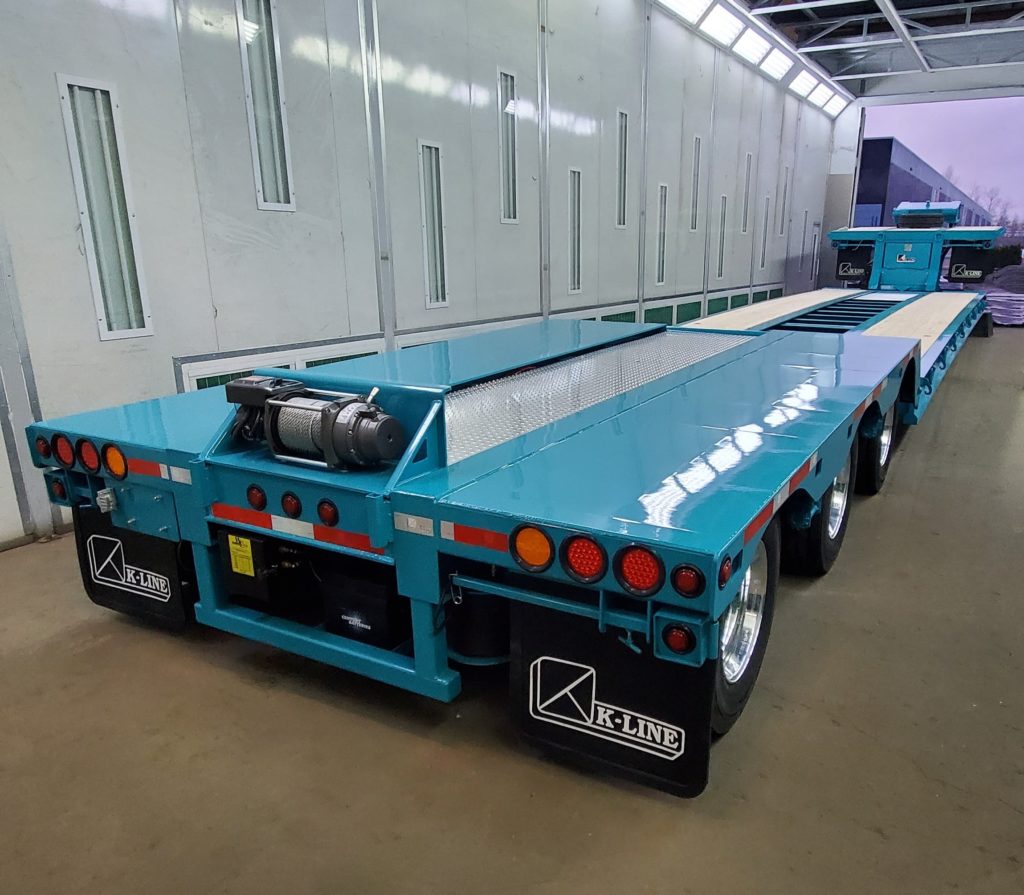 Back view of long blue trailer with multiple wheels